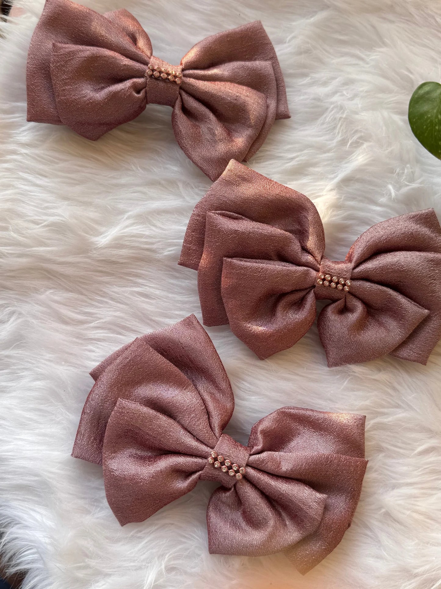 Three rose gold silk hair bows with stone detailing by Bows and Bags India on white fur background, handmade accessories