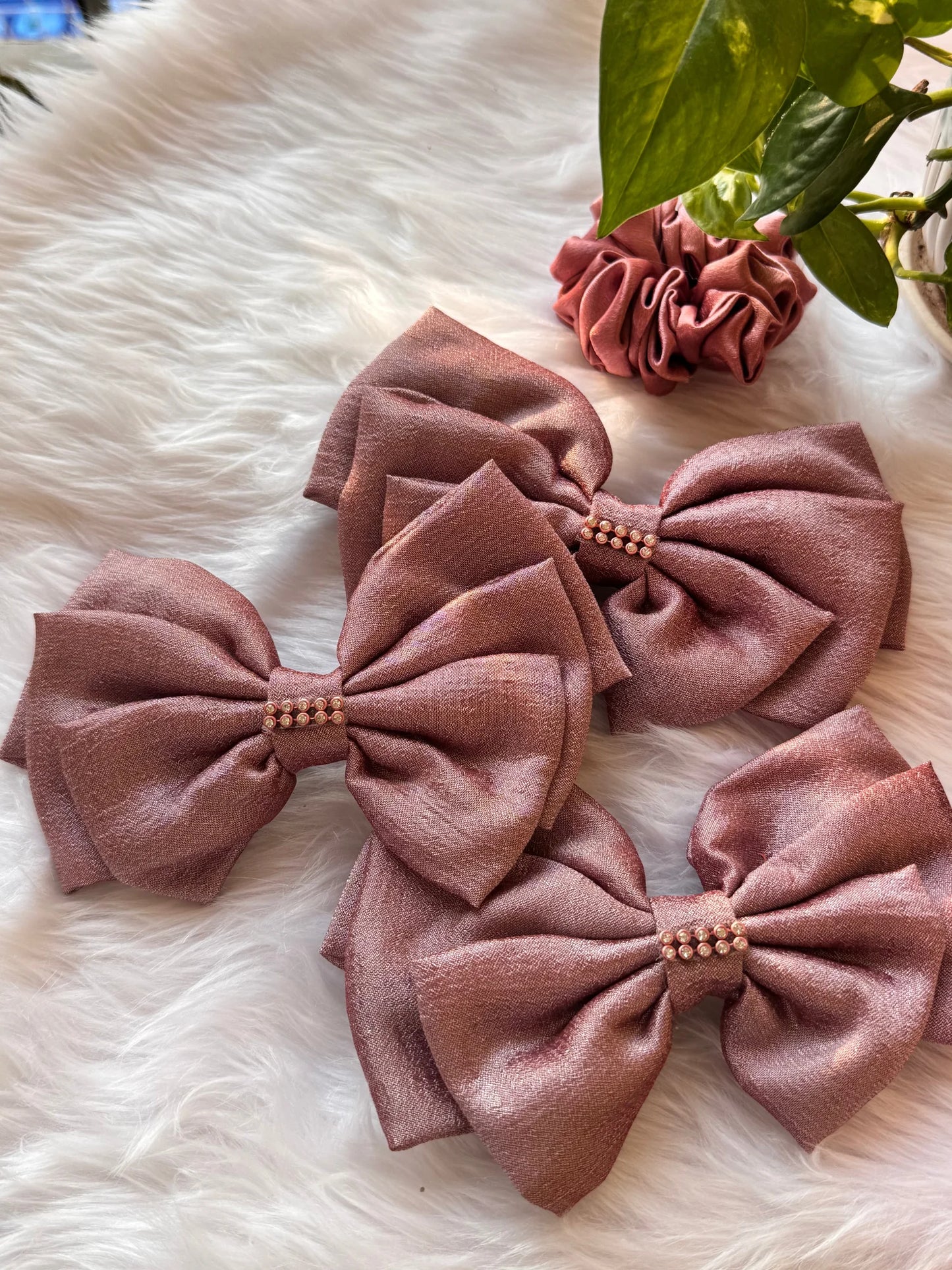 Rose gold silk hair bows with pearl stone details displayed on white fur by Bows and Bags India handmade collection