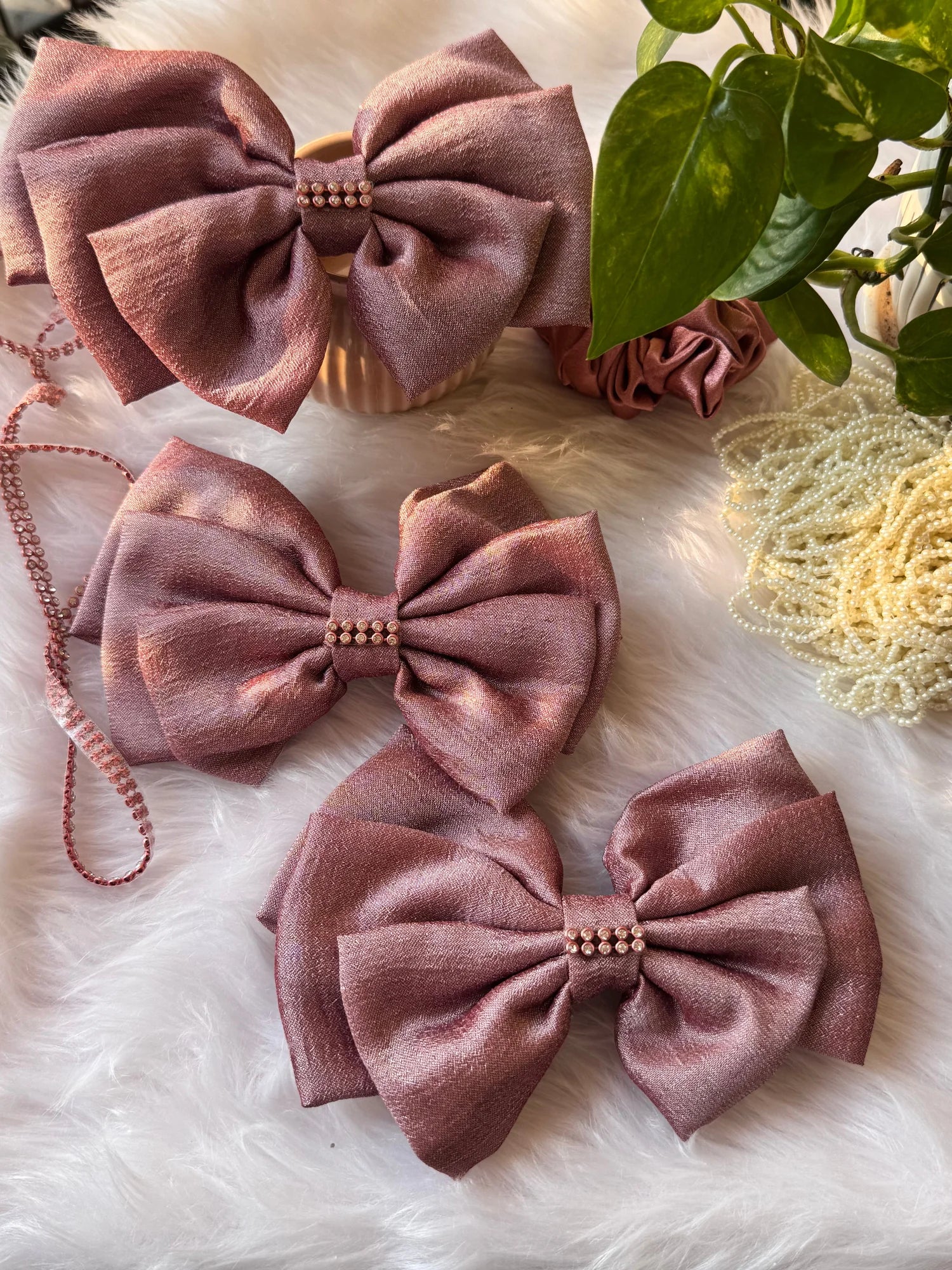 Rose gold silk hair bows with pearl stone detail by Bows and Bags India, handmade accessories displayed on white fur with