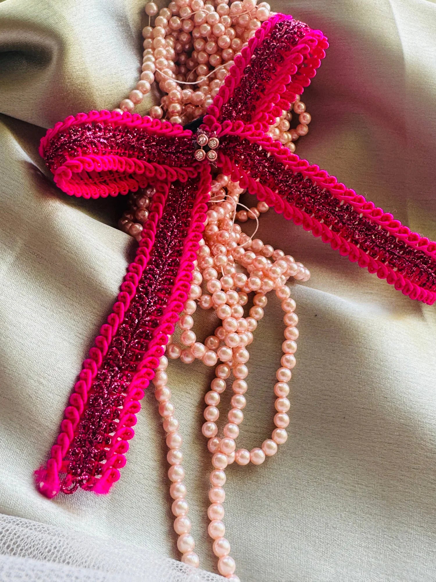 Handmade Rose Roosevelt pink glitter bow hair clip with pearl beads by Bows and Bags India, detailed lifestyle flat lay shot