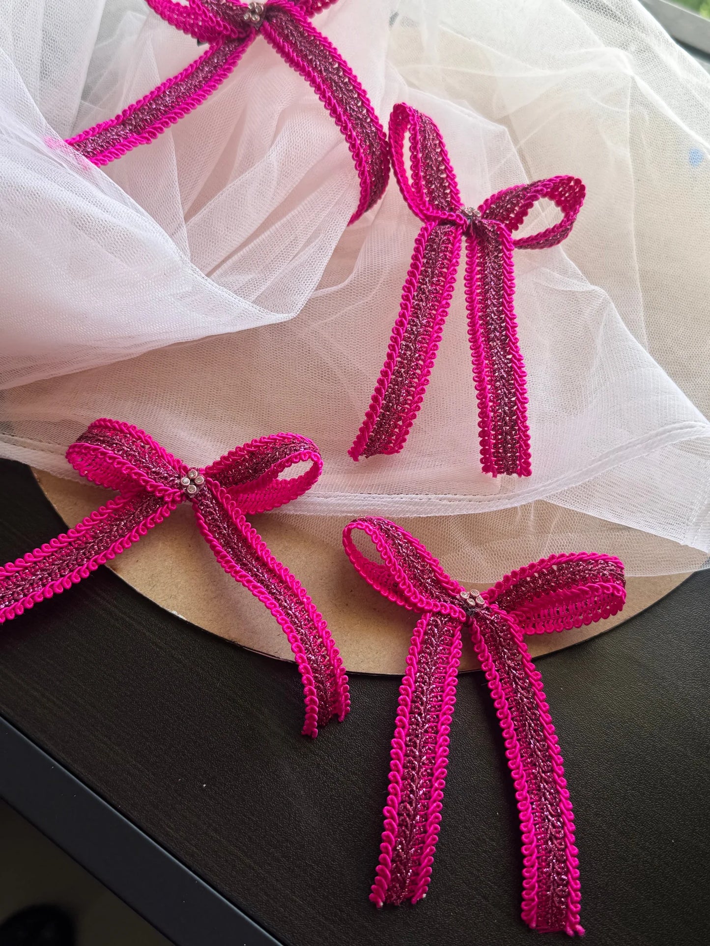 Magenta knitted hair bows with sequin detail arranged on tulle, handmade accessories by Bows and Bags India