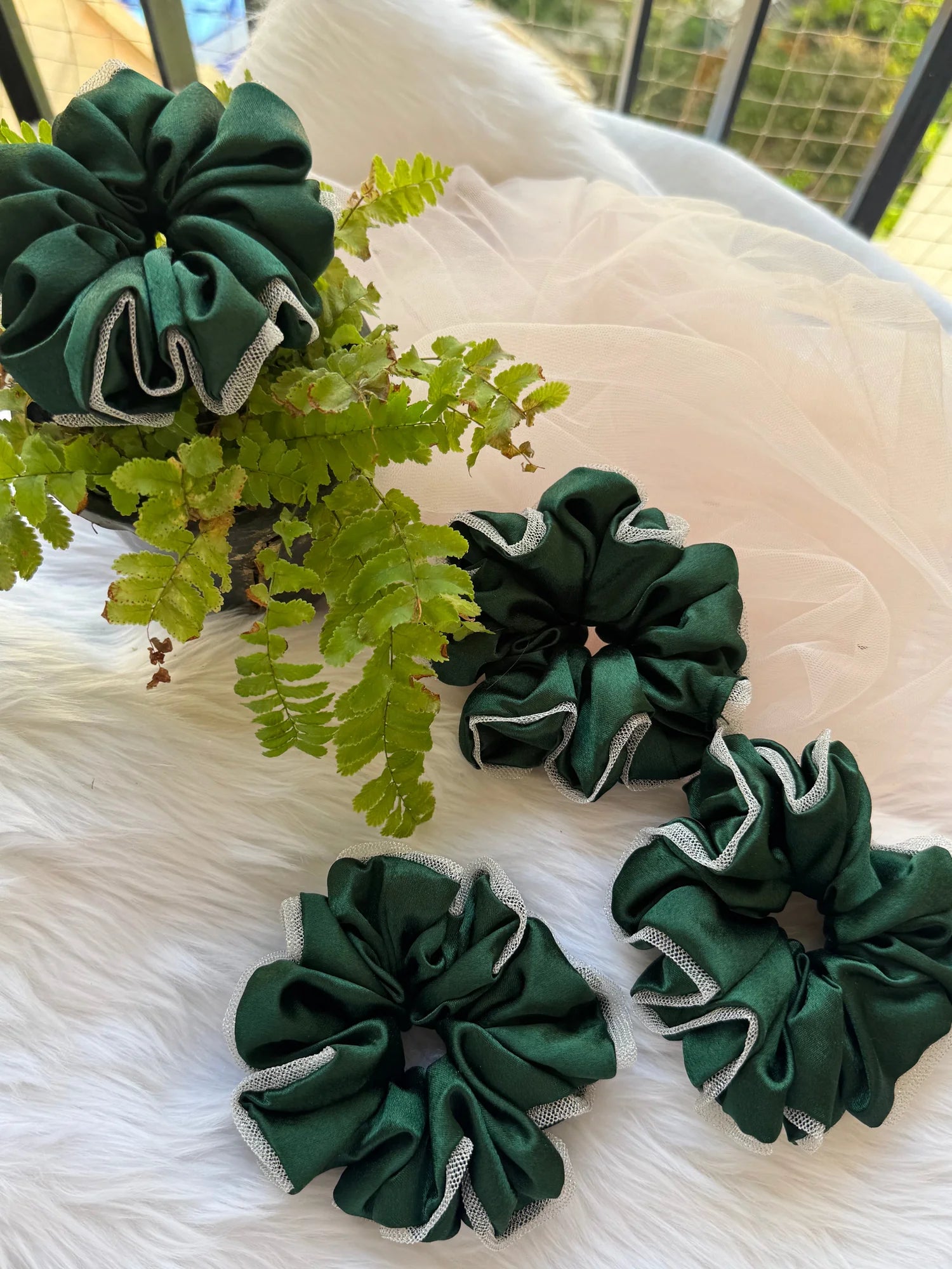 Dark green satin scrunchies with silver net borders displayed with fern leaves, handmade hair accessories by Bows and Bags