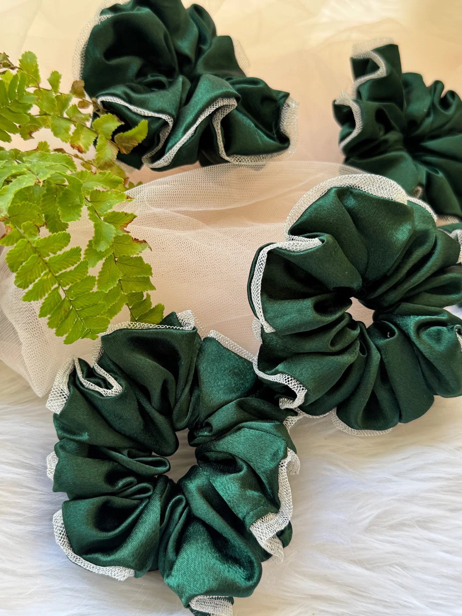 Dark green satin scrunchies with silver net borders arranged on white tulle, handmade hair accessories by Bows and Bags India