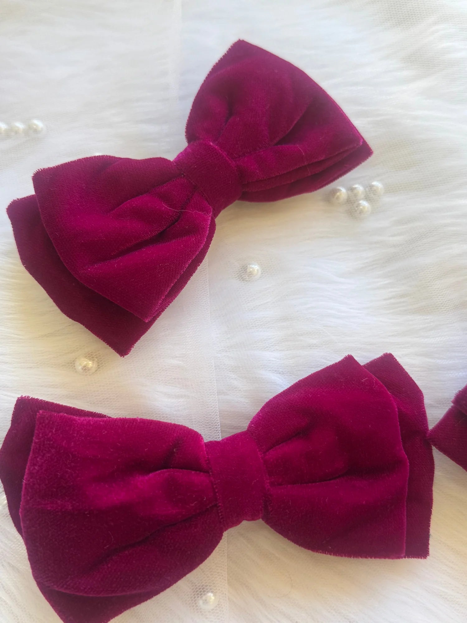 Magenta pink velvet hair bows by Bows and Bags India displayed on white fur with pearl accents, showcasing handmade premium