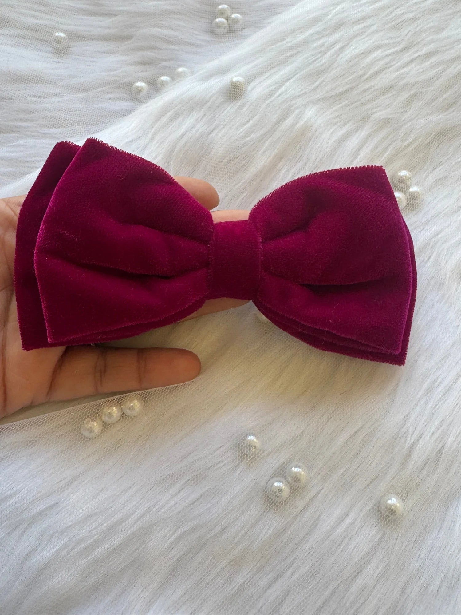 Magenta pink velvet hair bow held in hand, showing luxurious texture and bold color - Bows and Bags India handmade accessory