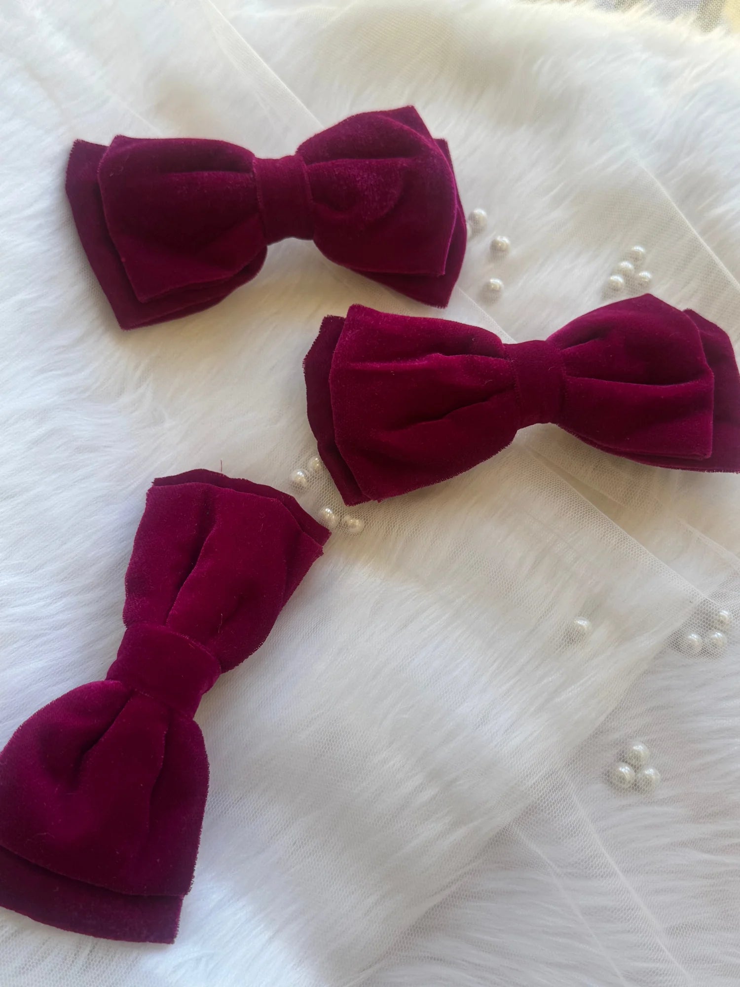 Three magenta velvet hair bows by Bows and Bags India displayed on white tulle fabric, showcasing handmade texture and