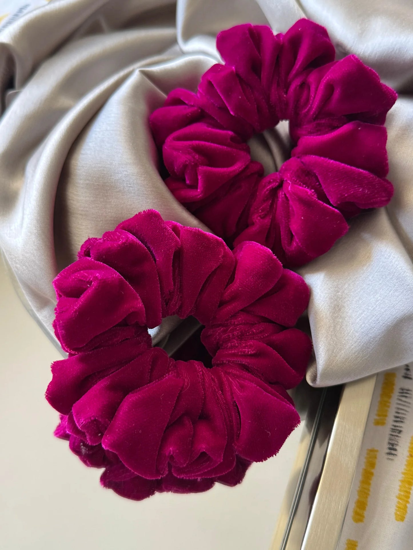 Hot pink luxe velvet scrunchie by Bows and Bags India displayed on cream fabric, showing premium handmade hair accessory