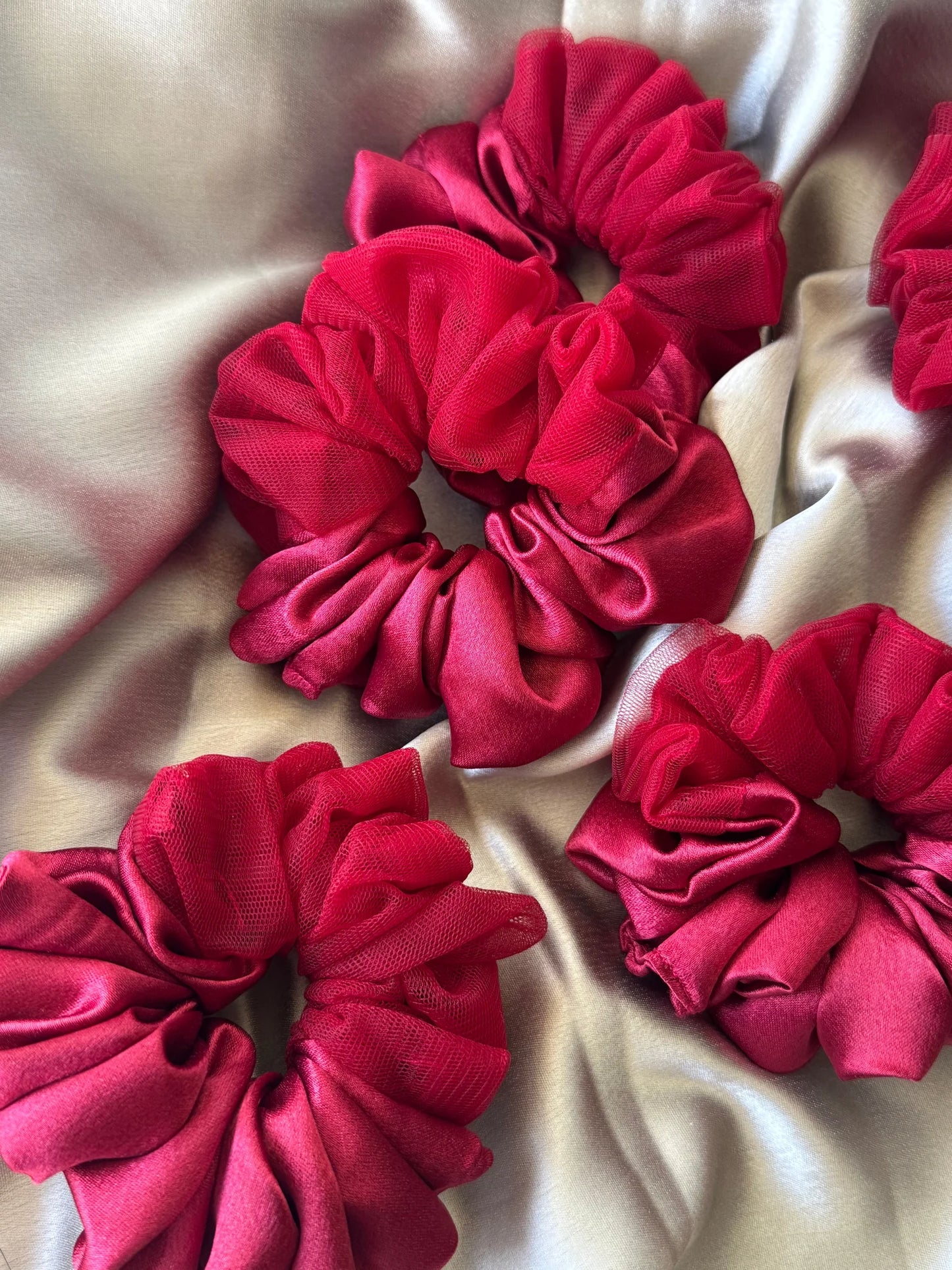 Crimson red satin scrunchies with sheer net detailing by Bows and Bags India, close-up texture view on cream fabric