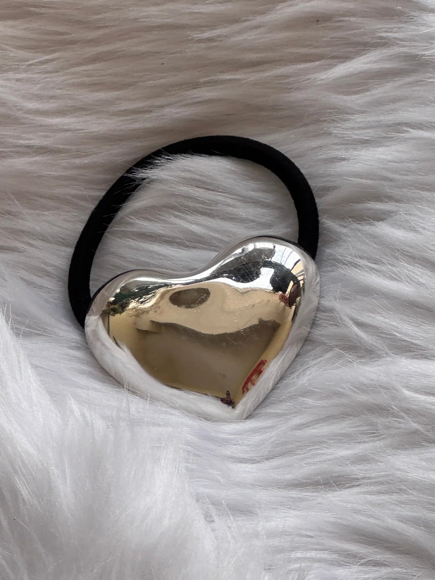 Silver heart metal rubber band hair tie with polished chrome finish on soft white fur by Bows and Bags India