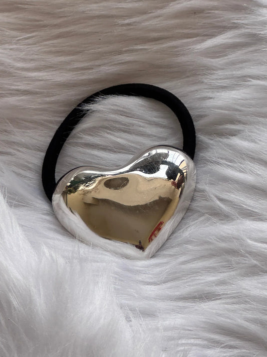Silver heart metal rubber band hair tie with polished chrome finish on soft white fur by Bows and Bags India