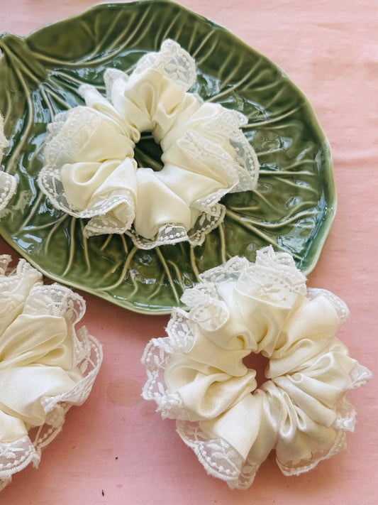 Cream satin scrunchies with delicate embroidered lace by Bows and Bags India, displayed on green leaf dish