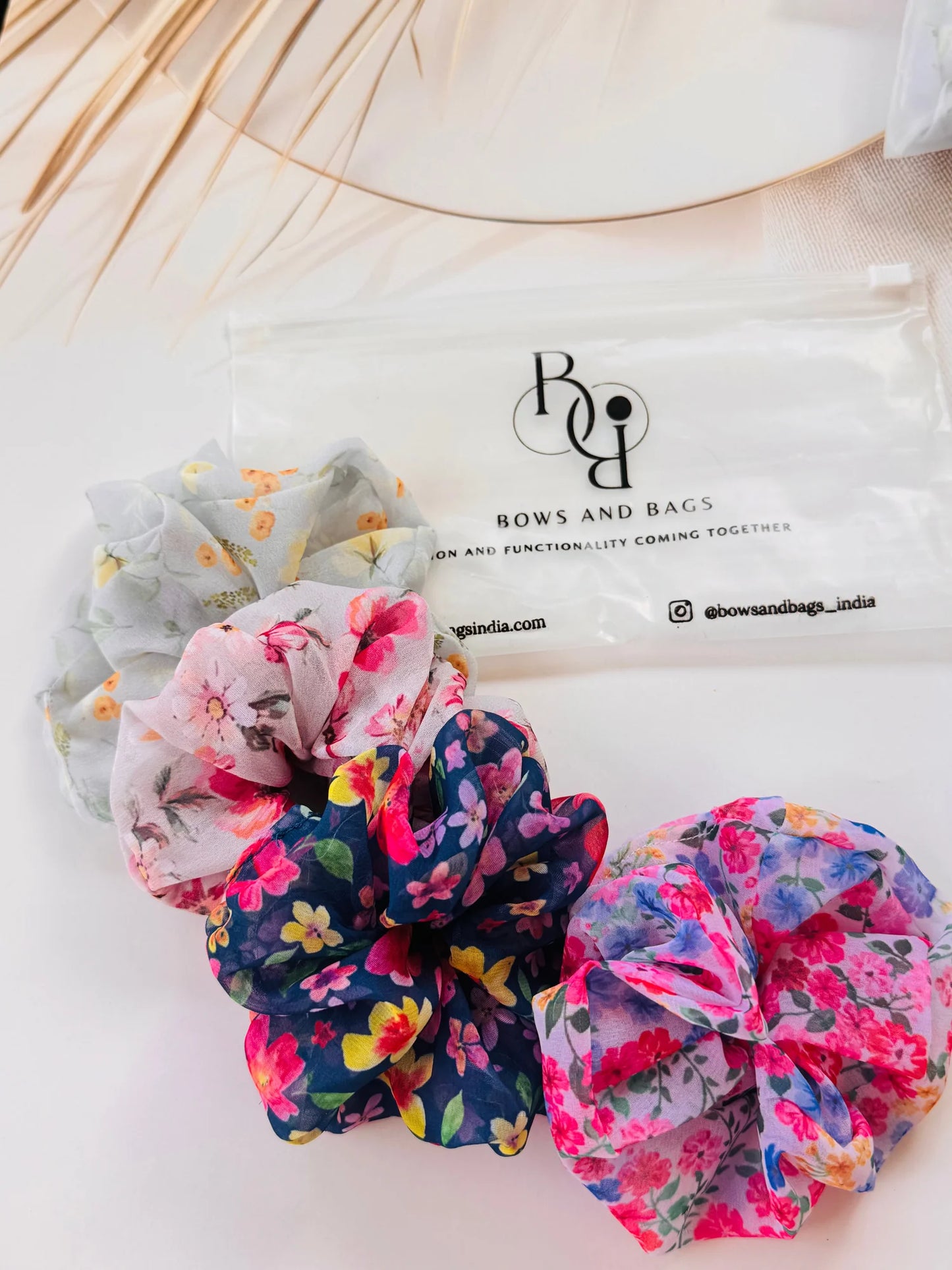 Bows and Bags India floral georgette scrunchies pack displayed with branded packaging and decorative elements in flat lay
