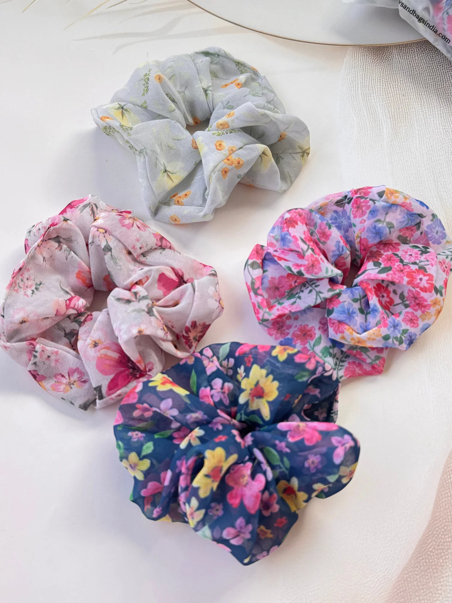 Four assorted floral georgette scrunchies from Bows and Bags India handmade hair accessories collection displayed on white