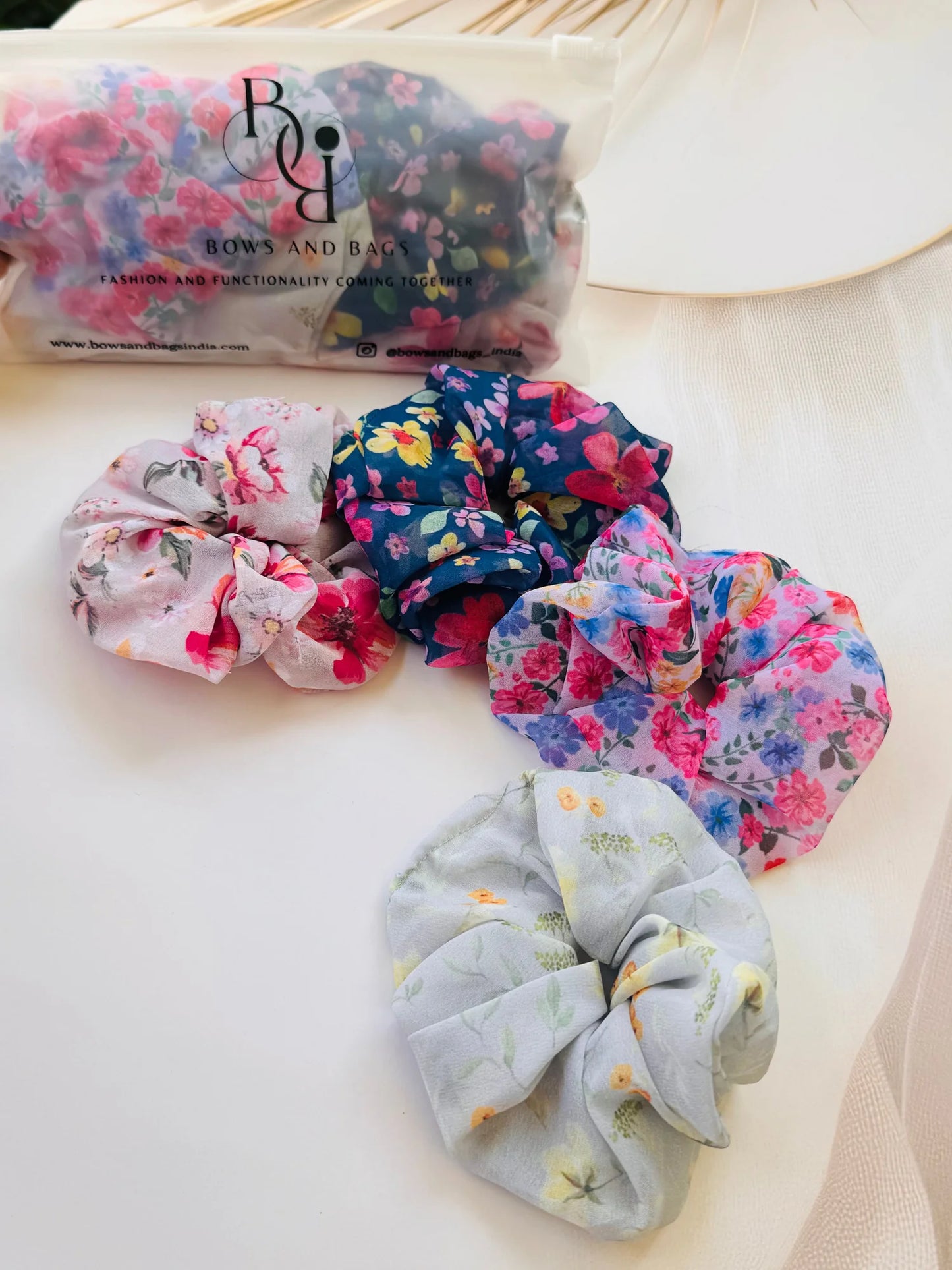 Assorted floral georgette scrunchies pack of 4 by Bows and Bags India displayed on white surface showing vibrant pink blue