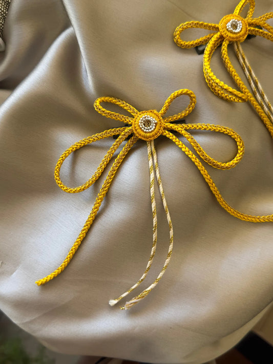 Golden rope bow hair clip with rhinestone center on cream fabric by Bows and Bags India