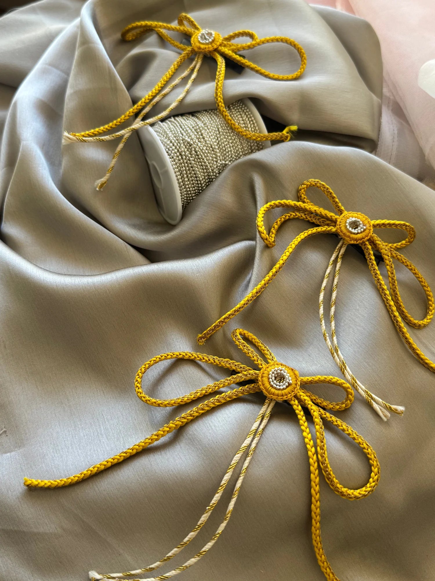 Golden handmade hair bow clips with rhinestone centers by Bows and Bags India, displayed on cream fabric with burlap detail