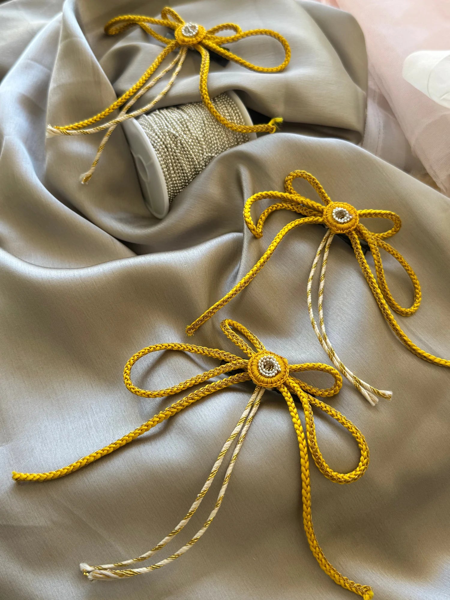 Golden Sun bow hair clips with rhinestone centers displayed on cream fabric, Bows and Bags India handmade hair accessories