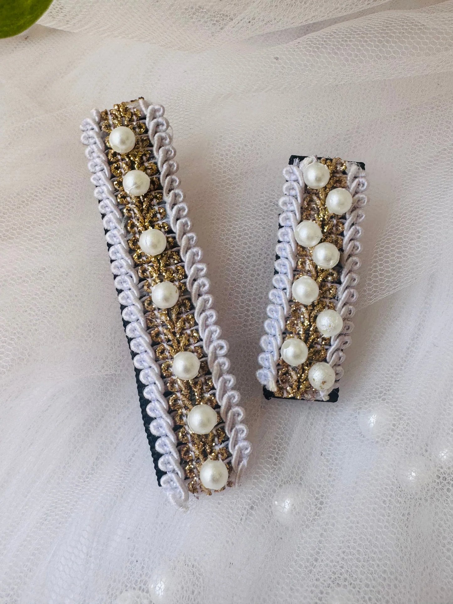 Pair of handmade pearl hair clips with gold embroidery and lavender lace trim by Bows and Bags India, displayed flat lay on