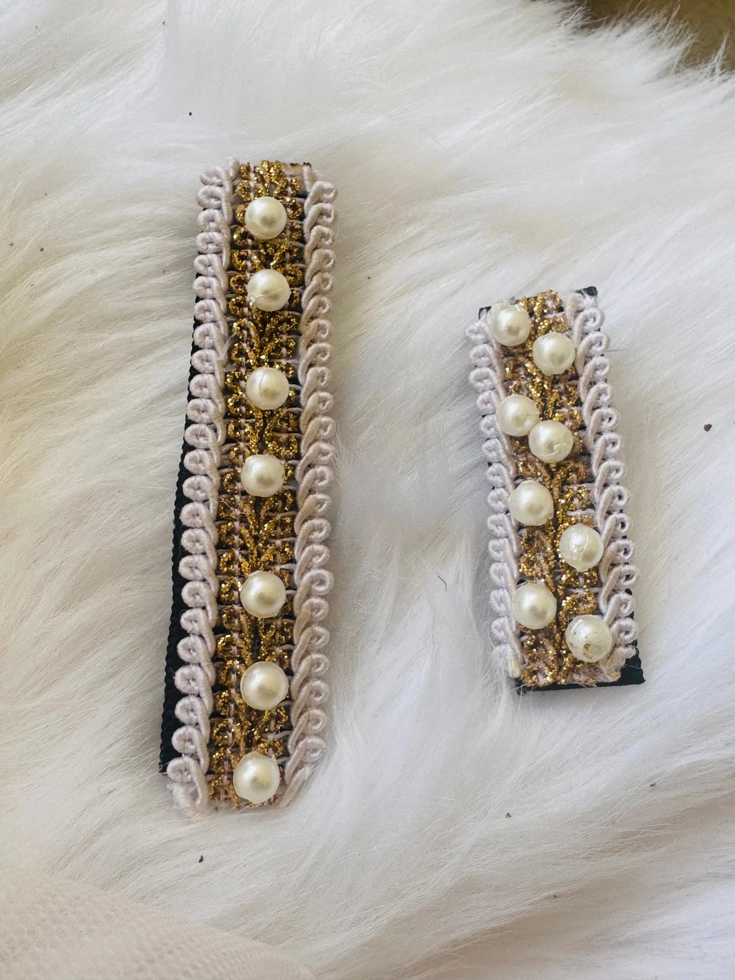 Pair of handmade pearl hair clips with gold glitter and lavender lace trim by Bows and Bags India, displayed flat lay on
