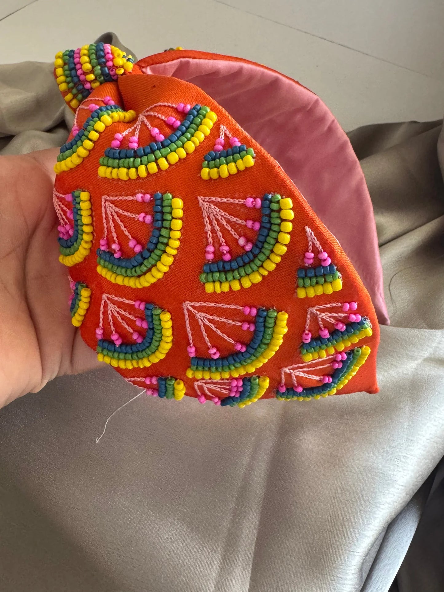 Close-up view of Tangerine Hawai handmade beaded satin headband showing vibrant orange fabric with multicolored beadwork