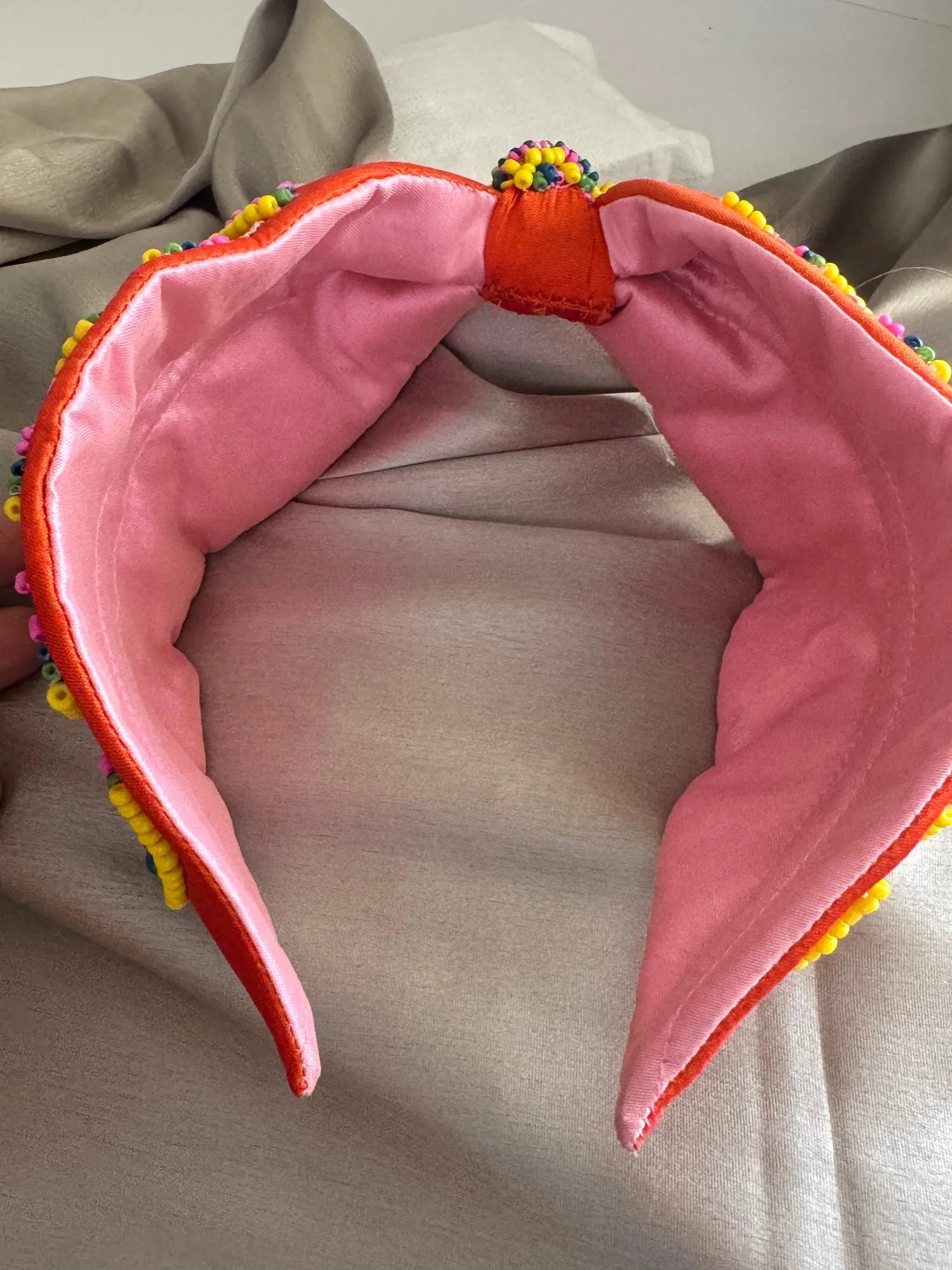 Tangerine Hawai handmade beaded satin headband displaying vibrant orange exterior with soft pink inner lining and