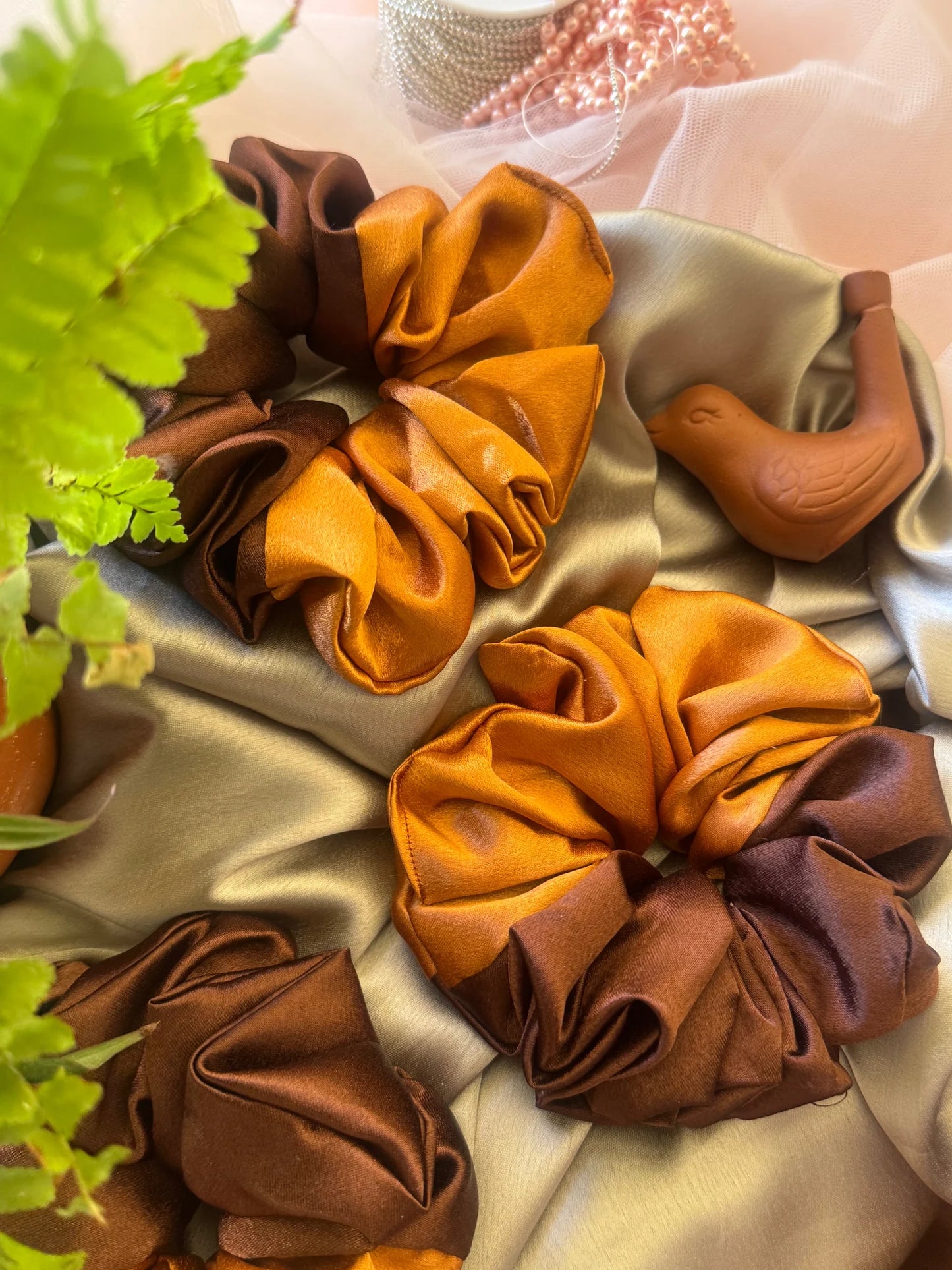 Handmade satin scrunchies in terracotta and brown tones by Bows and Bags India, displayed on neutral fabric with decorative