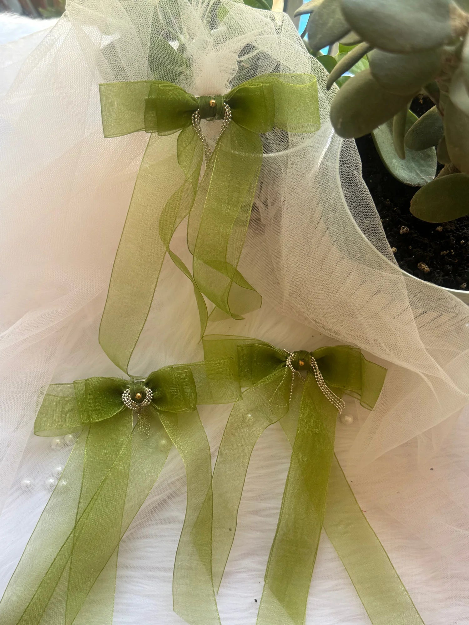 Light green organza handmade hair bow clip with silver chain detailing by Bows and Bags India, displayed on white tulle