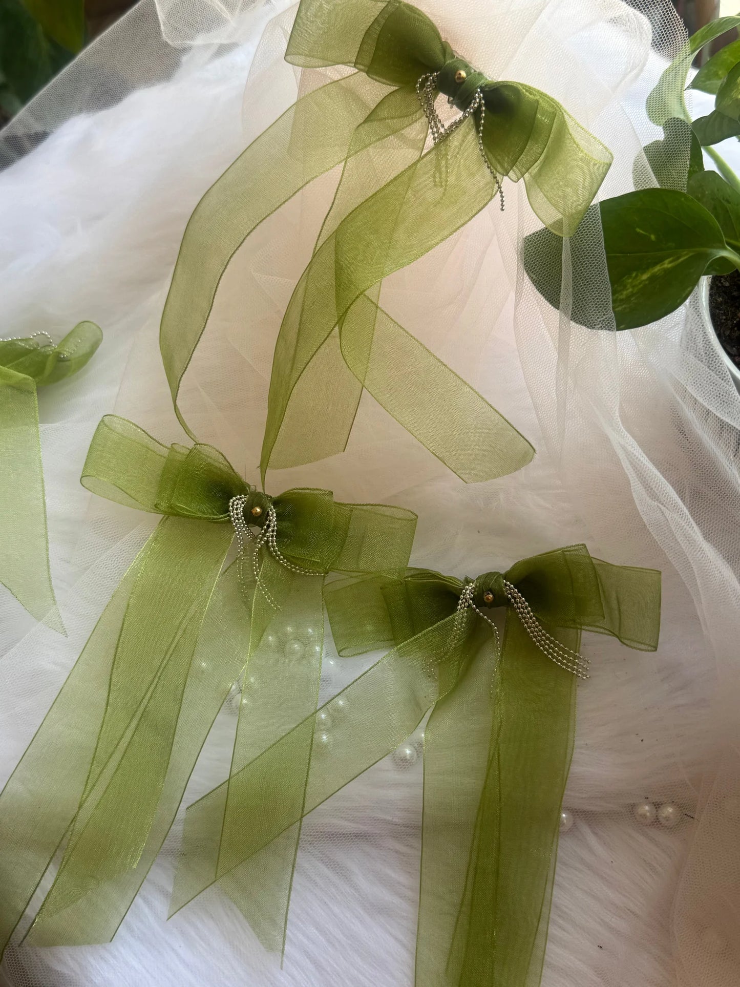 Light green organza hair bow clips with silver chain detailing by Bows and Bags India, displayed on white tulle fabric
