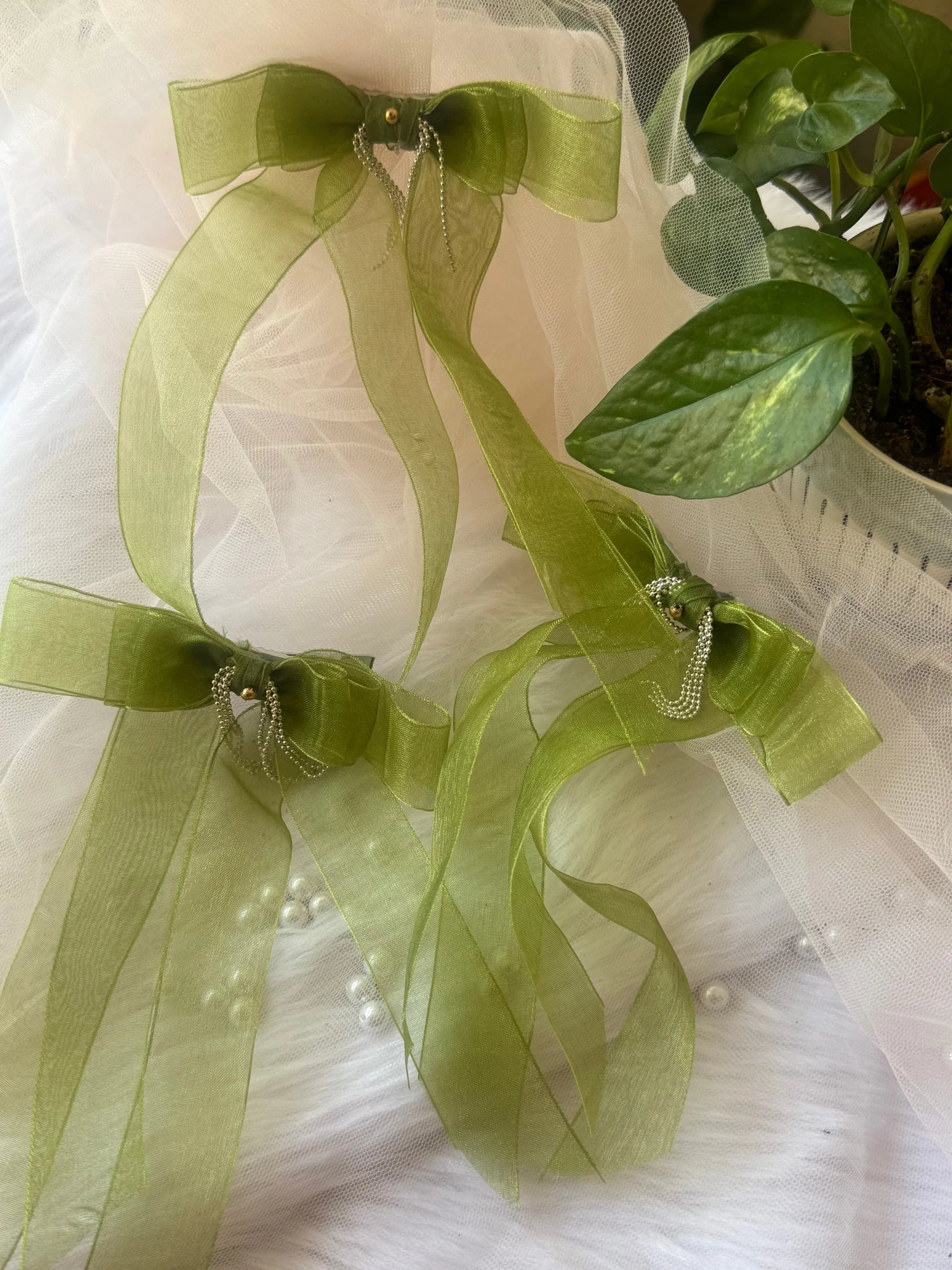 Light green organza hair bow clips with silver chain detailing by Bows and Bags India, displayed on white tulle fabric
