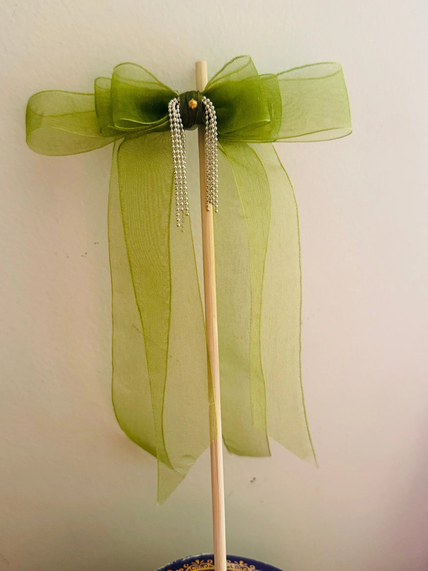Light green organza hair bow with silver chain detailing and wooden clip by Bows and Bags India, displayed on stand showing
