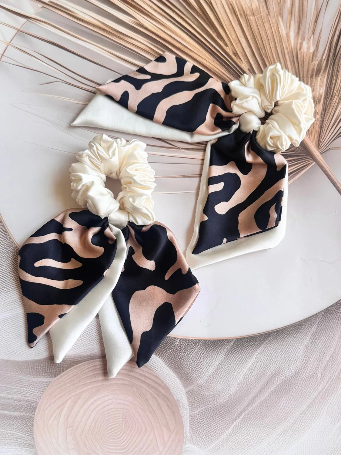 Animal print satin bow scrunchie with dual trailing tails displayed with cream silk elements, handmade by Bows and Bags India