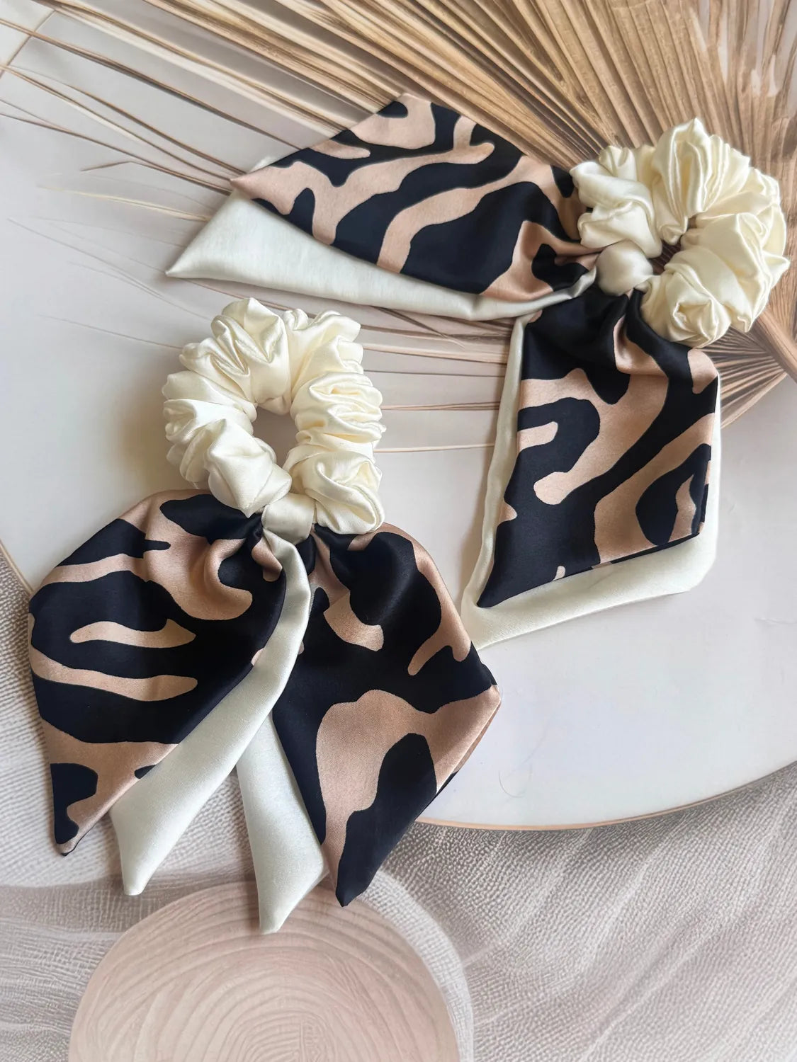 Handmade animal print satin bow scrunchie with dual trailing tails by Bows and Bags India, featuring black and camel